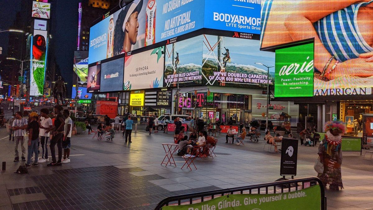 Documentary photograph of pedestrians, billboards and outdoor seating in Times Square on July 21, 2020.