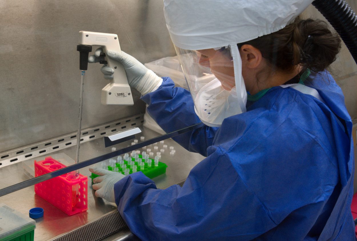 CDC scientist working with an H7N9 influenza specimen inside a laboratory, archival documentary image. Documentary photograph; original source credited to CDC / James Gathany.