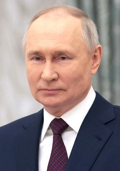 Head-and-shoulders photograph of Russian President Vladimir Putin in a dark suit and red patterned tie at a Kremlin ceremony, March 8, 2023.
