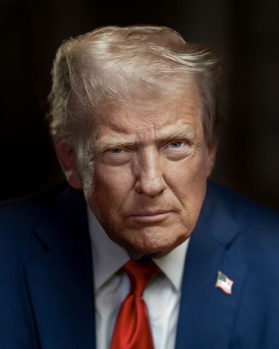 Official presidential portrait photograph of President Donald J. Trump, 2025: a close head-and-shoulders image in a blue suit, white shirt and red tie with a U.S. flag lapel pin, against a dark background.