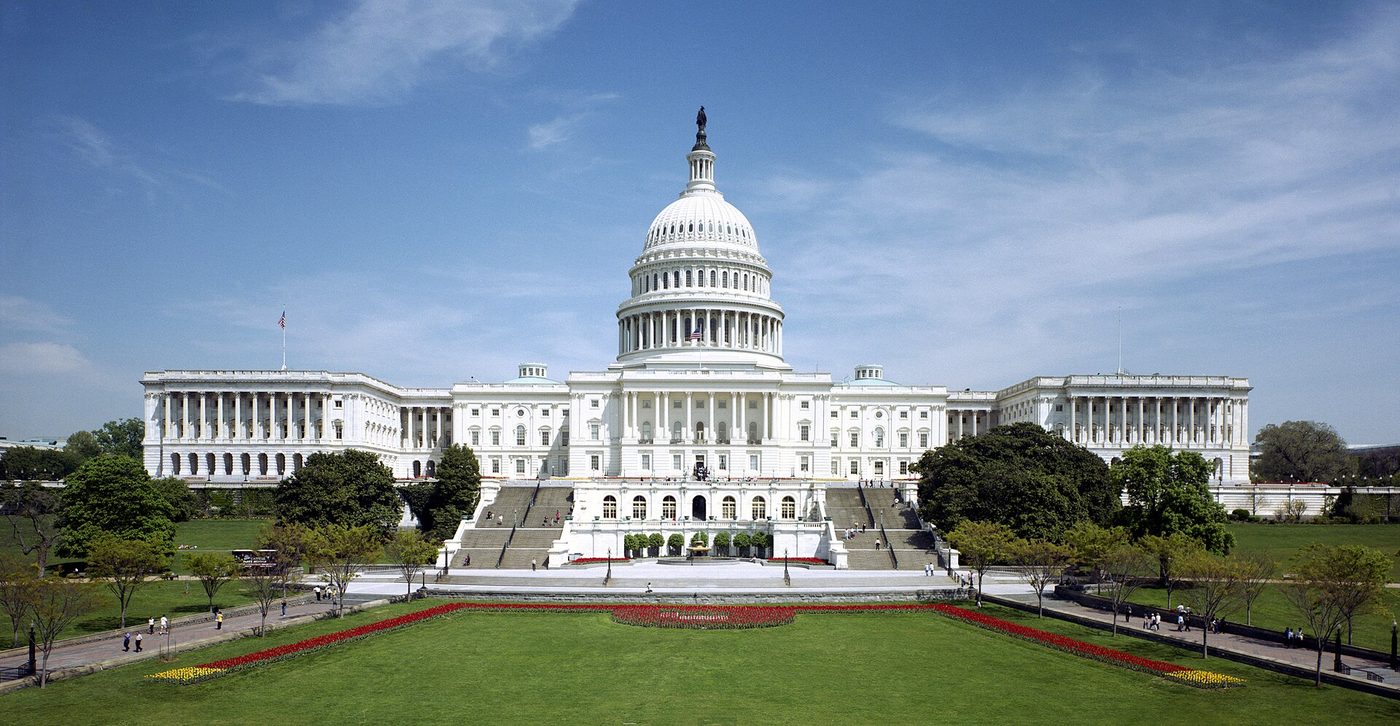 Photograph of the west front of the United States Capitol in Washington, D.C., with its white dome above a terraced lawn.