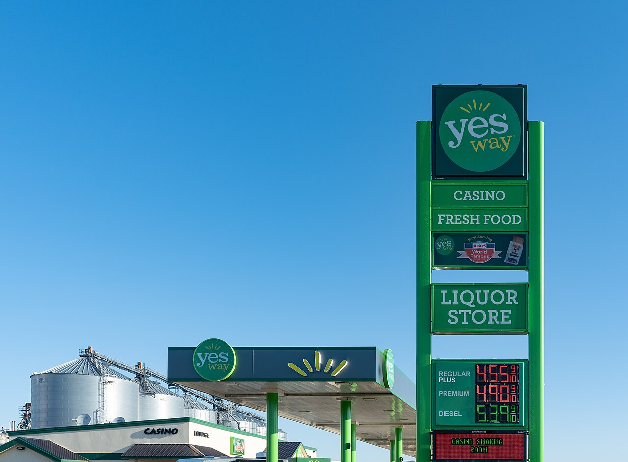 Roadside gas station sign showing fuel prices against a blue sky